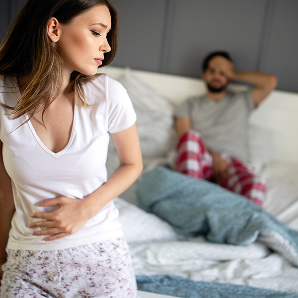 a woman standing on a bed with a man in the background
